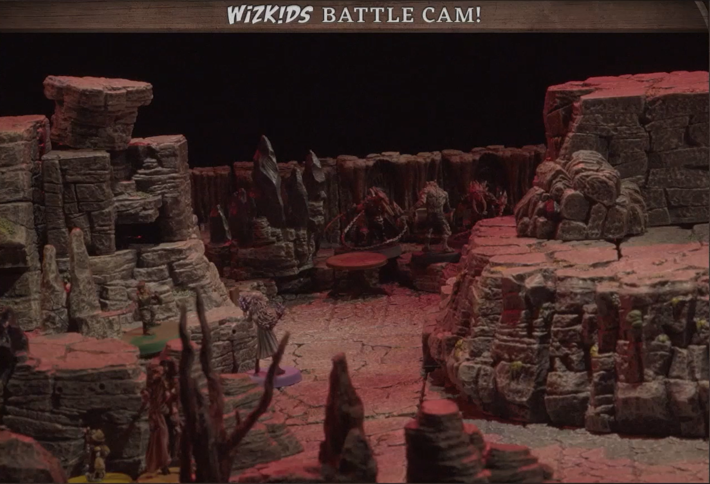 A battlemap of rock-walled space dotted with rock formations and stalagmites. Orym is on a ledge, Imogen is just below him, and Chetney in wolf form is facing against enemies deeper in.