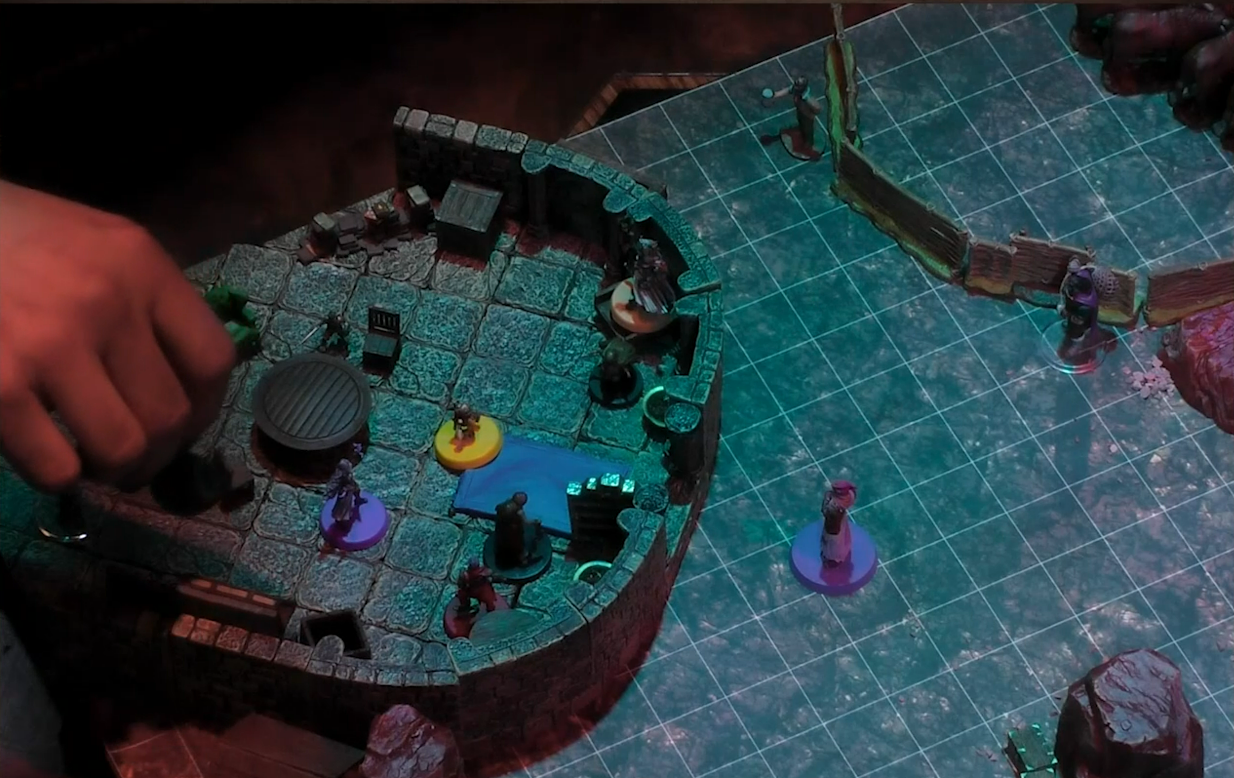 A battlemap of a rounded stone building with an expanse of flat ground outside. FCG, Orym, Imogen, Fearne, and other tokens are inside the building. A purple token stands outside at the entance. Two other tokens stand by a fenced area.