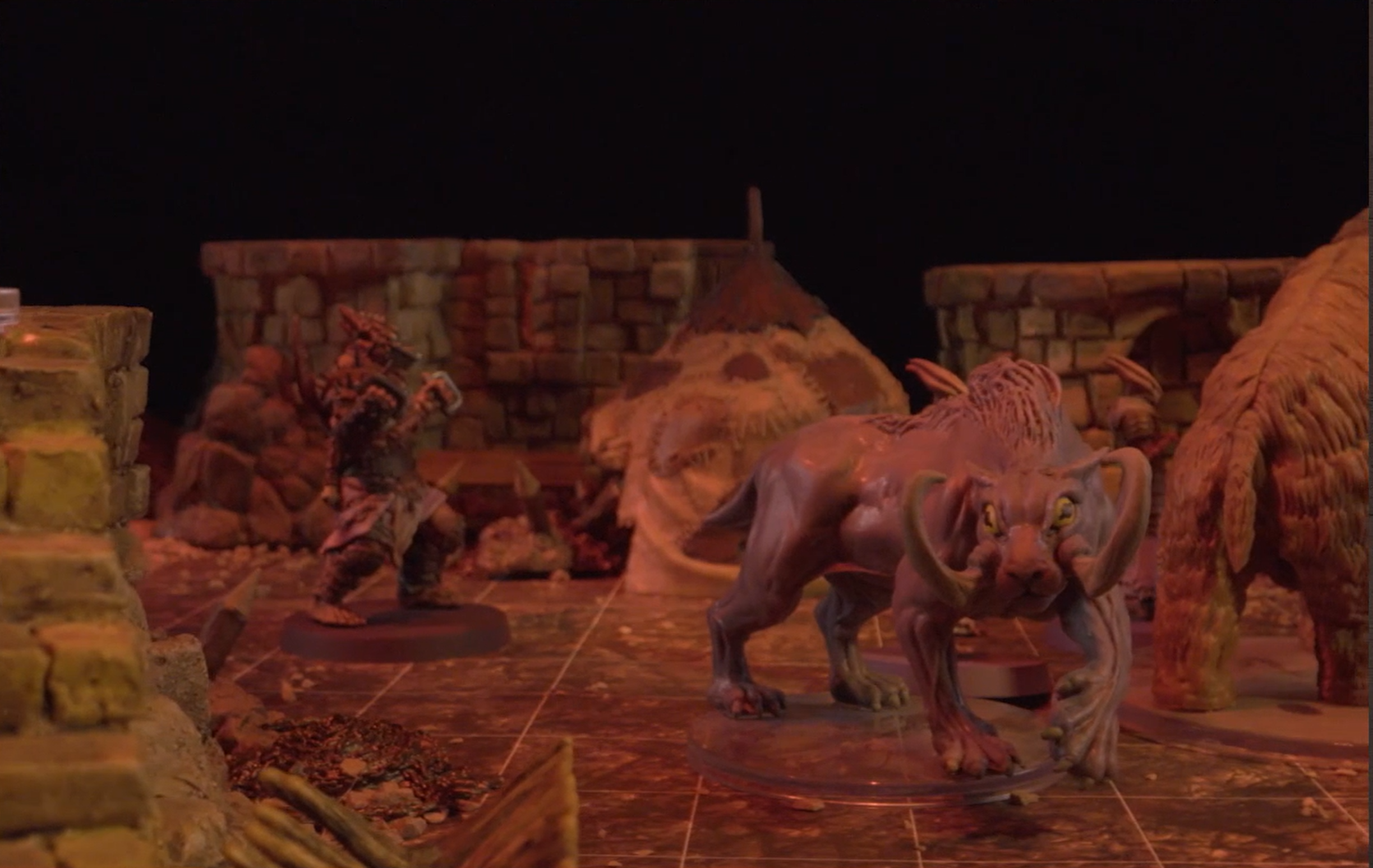 A tusked tiger-like creature facing the camera, with a wooly-mammoth-like creature next to it and a Reiloran behind it. The walls of buildings and a patchwork tent can be seen in the background.