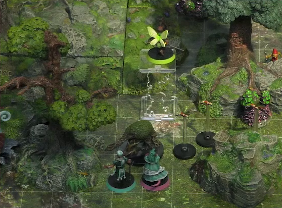 A battlemap of a forested glade. Thimble flies 10 feet in the air near a tree. Wicander and Tyranny face off against a shambling mound. Three pixies fly nearby. A red-capped gnome-like creature wielding a sickle looks on from behind a rocky outcropping.