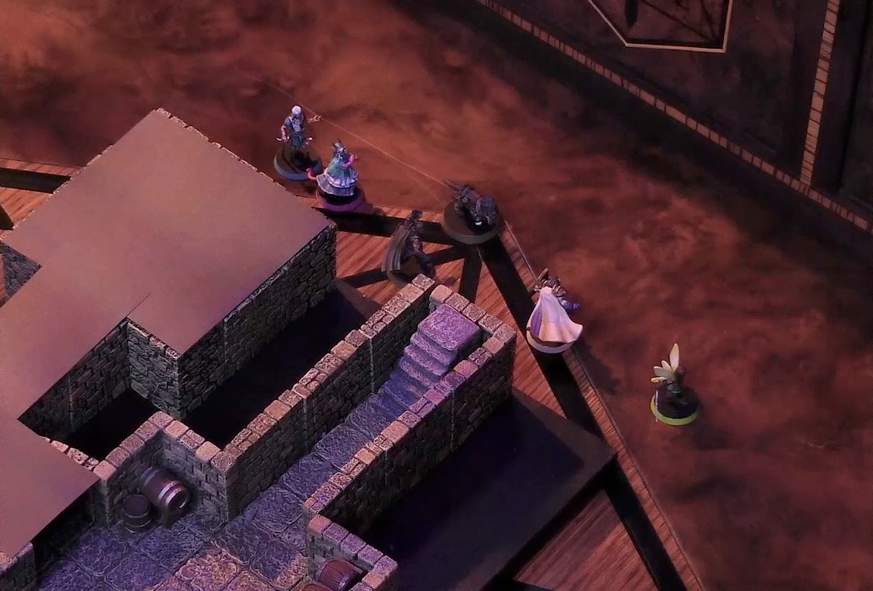 A battlemap of a small stone dungeon. Wicander, Tyranny, Kattigan, Wulferic, Teor, and Thimble stand on the table outside the map. In the map, a short set of stairs go down into a hallway which leads to a chamber containing some barrels against the walls. Another hallway leads off and turns a corner into a second chamber. Both this final hallway and chamber are obscured with black construction paper.