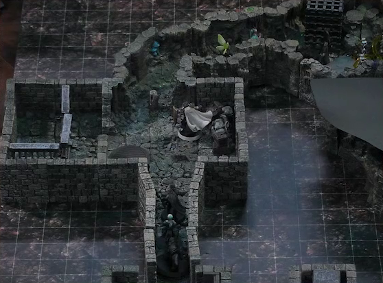 A battlemap of a stone dungeon. Wulferic, Wicander, and Kattigan stand single-file in a narrow hallway leading into a chamber. In that chamber, Teor stands in the corner with some wooden containers. Across the room are metal bars resembling an empty jail cell. Deeper into the dungeon is a naturally-formed chamber, where Thimble and Tyranny face off against a basilisk, a black-cloaked knight, and some armored guards with spears. Two large black cube-shaped cages are against one wall, and a stone slab is against the opposite wall.
