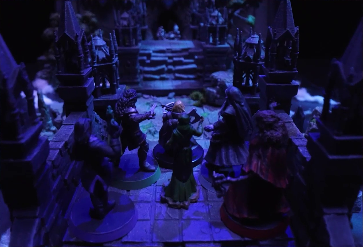 A battlemap of an ornate stone bridge over water. Julien, Mozor, Vaelus, Occtis, Aranessa, and Thaisha stand at one end. Blurry in the distance, six armored soldiers led by Frons Tachonis stand before a gate in a wall at the other end.