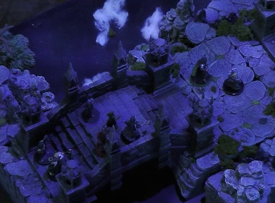 A battlemap of an ornate stone bridge over water. Vaelus, Occtis, Aranessa, and Thaisha stand at one end, with Julien and Mozor further ahead down some steps. Behind them all at the edge of the bridge are two druids. White foam caps waves in the water below.