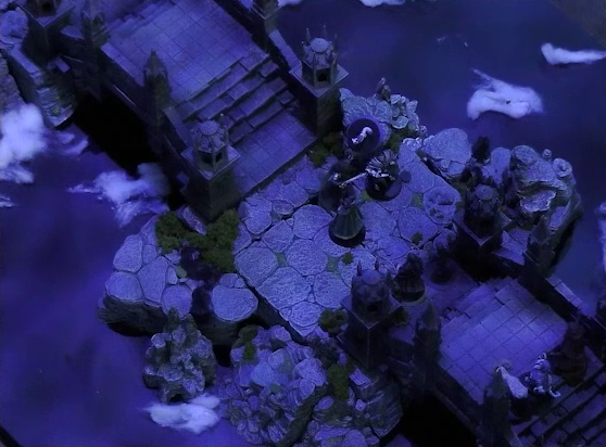 A battlemap of an ornate stone bridge over water. Julien, Aranessa, and Pin face off against the heavily-armored Frons Tachonis about halfway along the bridge. Approaching them are Vaelus and Occtis, and a bit further back Hala, an aspirant demon, and Thaisha. White foam caps waves in the water below.