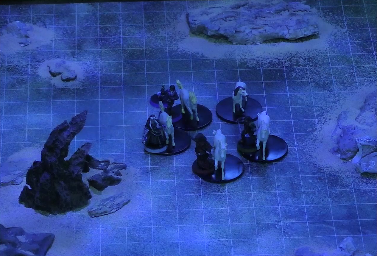 A battlemap of a flat, sandy expanse under the cover of night. Occtis, Pin, Vaelus, Thaisha, and Julien stand in a circle with their five white horses. Some jagged rocky formations jut from the otherwise empty landscape.