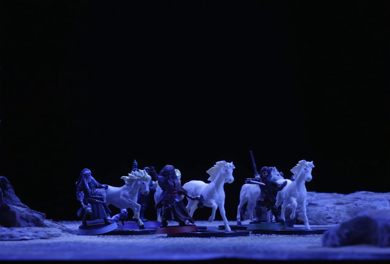 A battlemap of a flat, sandy expanse under the cover of night. Occtis, Pin, Vaelus, Thaisha, and Julien stand in a circle with their five white horses. Some jagged rocky formations jut from the otherwise empty landscape.