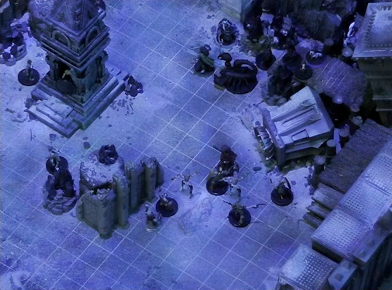 A battlemap of stony desert ruins under the cover of night. A short tower stands in the middle of the battlemap. Julien and Vaelus face off against a giant scorpion to the right of the tower, while Thaisha and Gaya Seremai face off against some skeletons a short distance away. A downed skeleton is in the tower. Several other skeletons approach the tower.