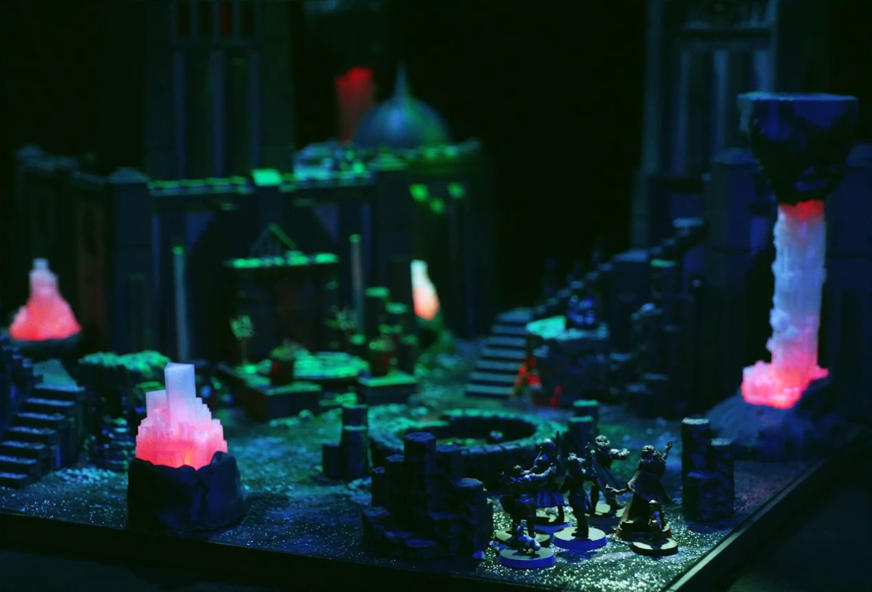 A battlemap of a walled courtyard under cover of night. Gaya Seremai, Pin, Vaelus, Occtis, Julien, Thaisha, and Dr. Talter stand beside a circular pool of dark red blood. Beyond the pool of blood is a metal sacrificial platform with two candelabras at the base of a tall tower. Stairs lead up another tower to the right, and a tower with a domed roof is in the background. Interspersed throughout the chamber are at least five red glowing crystal pillars.