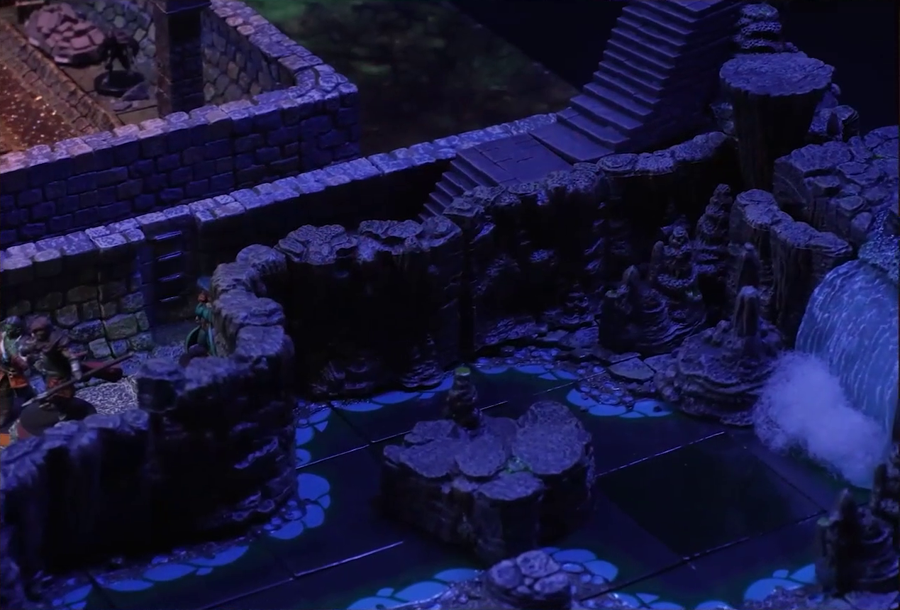 A battlemap of a stone underground area in the sewer. A waterfall feeds into a river, which runs beside a hallway where Halandil, Azune, and Murray stand. A flight of stairs leads down into the hallway. A room is off from the hallway. A Crow Keeper is visible at the edge of the room.