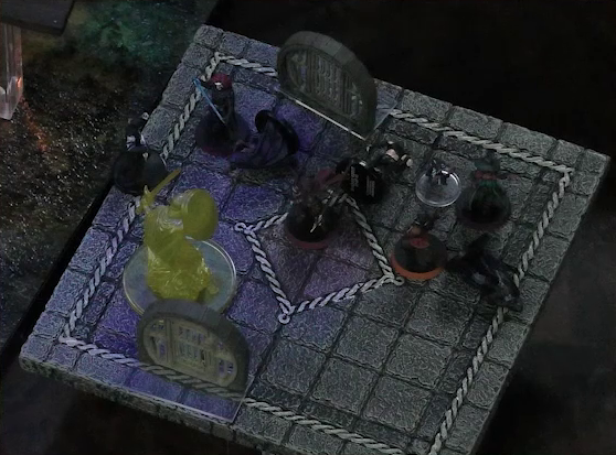 A battlemap focused on a stone platform. Bolaire, Azune, and Halandil stand over a fallen Crow Keeper each, while Murray stands next to Demodus Blix. One Crow Keeper remains standing next to a knight made of light.