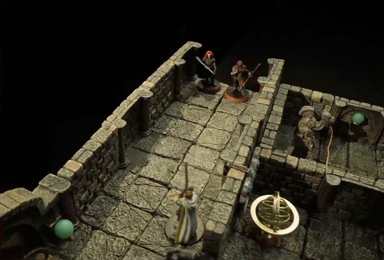 A battlemap of a stone hallway. Bolaire and Azune stand at one end, while a white-caped Halovar guard wielding a sword stands down the hall from them near the entrance to a chamber. Inside the chamber is an orrery. An unconnected adjacent hallway has a grotesque at one end. Some green globes are spaced along the walls in the hallways.