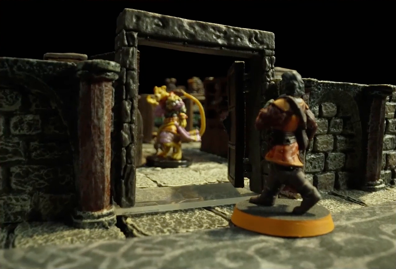 A small battlemap of a library chamber focused on Halandil standing in the open stone doorway to the library. Out-of-focus inside the room is a yellow Nama.