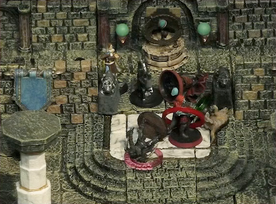 A battlemap of a large stone banquet chamber with surrounding hallways. Bolaire and a Timmonish knight face off against two assassins entering the chamber through its north entrance. Azune lies downed on the ground. A fallen Hound of the King with a “POISONED” status ring around its miniature lays on the ground just inside the entrance. Bolaire has a red status ring around his miniature, and a downed assassin has a “CONCENTRATION” status ring.