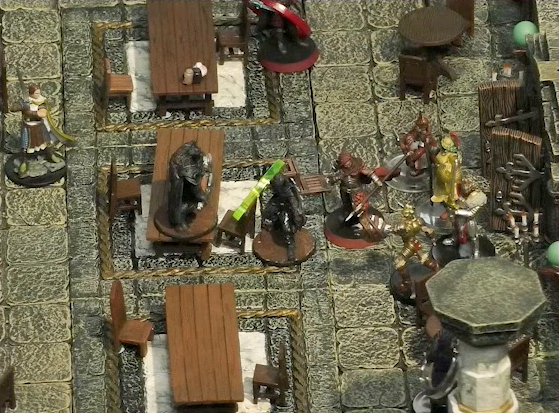 A battlemap of a large stone banquet chamber with surrounding hallways. An assassin with a green status ring stands in between Azune and another assassin, who is standing on a table. Behind Azune are a number of guards entering through the east entrance to the chamber. Bolaire with a red status ring is almost out of frame at the top of the image. A Timmonish knight approaches from the west.