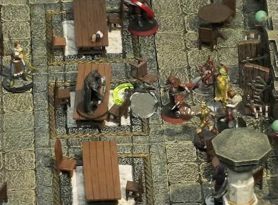A battlemap of a large stone banquet chamber with surrounding hallways. An assassin with a green status ring lies on the ground in between Azune and another assassin, who is standing on a table. Behind Azune are a number of guards entering through the east entrance to the chamber. Bolaire with a red status ring is almost out of frame at the top of the image. A Timmonish knight approaches from the west.