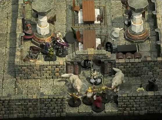 A battlemap of a large stone banquet chamber with surrounding hallways. Filoneus Halovar stands at the open south entrance to the chamber with his dogs Wrath and Judgement on either side of him. A number of guards approach them, attempting to enter the room. Inside the chamber, King Augustus Valian, a druid, and a Timmonish knight face off against assassins. Murray sides behind a nearby pillar. A downed Hound is nearby. On the other side of a table from this fight lays Photarch Yanessa and an attendant Lux.