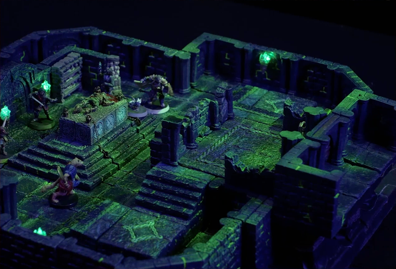 A battlemap of a stone chamber. A stone altar is in the center with a skeletal corpse on top of it, next to which stand Occtis and Pincushion. Around the altar are Thimble, Julien, Teor, and Talcydimir. Behind the altar is a circular hole leading into the wall. Two staircases on either side of the hole lead up to a door with a portcullis. The room is lit by a sickly green glow emanating from torches on the walls.