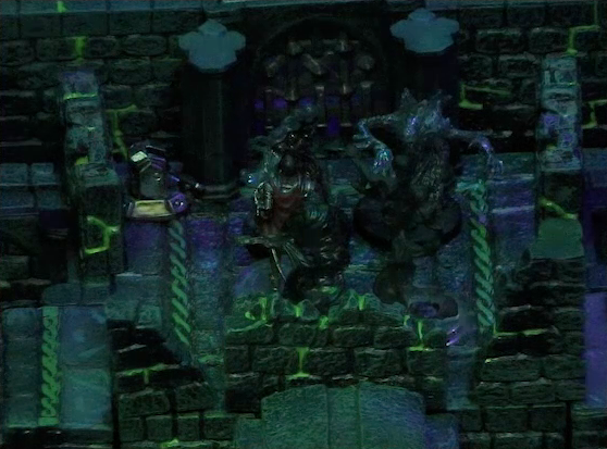 A battlemap of a stone chamber. Four shadows gather at the top of a staircase. Behind them is a door blocked by a portcullis, next to which is a lever in the down position.