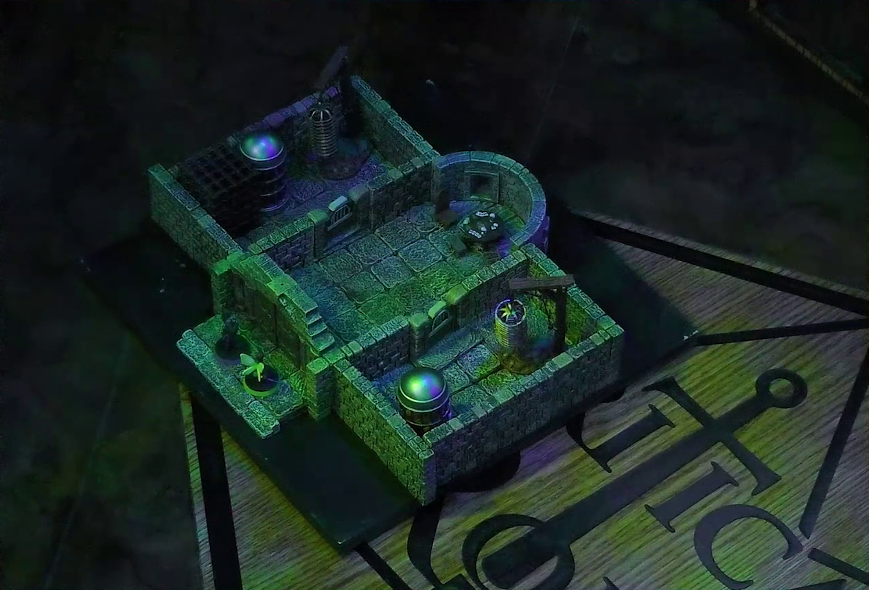 A battlemap of a stone aviary split into three rooms. Occtis and Thimble stand outside a closed door into the main chamber, in which is a circular table with a card game abandoned on it. To the left of the main chamber is a closed door leading to a room with a large cubic black metal cage, a large cylindrical silvery metal cage, and a large cylindrical metal hanging cage resembling a bird cage. To the right of the main chamber is a closed door leading to a room with the same kind of silvery metal cage and hanging cage, although there is no large cubic cage.