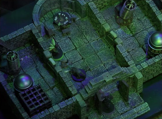 A battlemap of a stone aviary split into three rooms. Occtis stands in the open door to the main chamber, facing off against a ghoul. Inside the main chamber Thimble and Occtis’s undead monitor lizard flank another ghoul. At the rear of the chamber is a circular table with a card game abandoned on it. To the left of the main chamber is a closed door leading to a room with a large cubic black metal cage, a large cylindrical silvery metal cage, and a large cylindrical metal hanging cage resembling a bird cage. To the right of the main chamber is a closed door leading to a room with the same kind of silvery metal cage and hanging cage, although there is no large cubic cage.