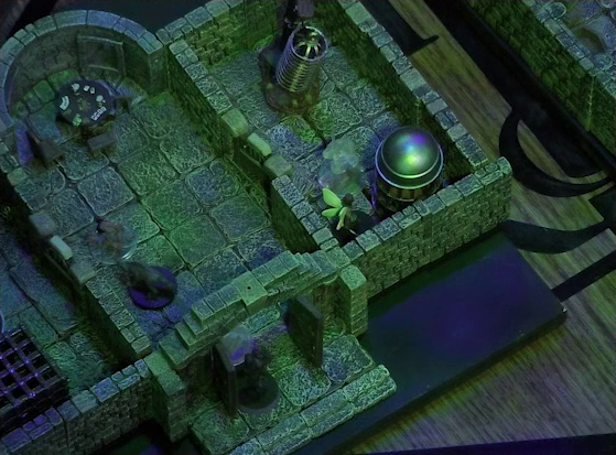 A battlemap of a stone aviary split into three rooms. Occtis stands in the open door to the main chamber, facing off against a ghost. Inside the main chamber Occtis’s undead monitor lizard faces a ghoul. Thimble is in a room to the right of the main chamber in front of a large cylindrical silvery metal cage, with another ghost to her left. At the rear of the main chamber is a circular table with a card game abandoned on it. To the right of the main chamber is a closed door leading to the room with the silvery cage with Thimble in front of it, as well as a large cylindrical metal hanging cage resembling a bird cage.