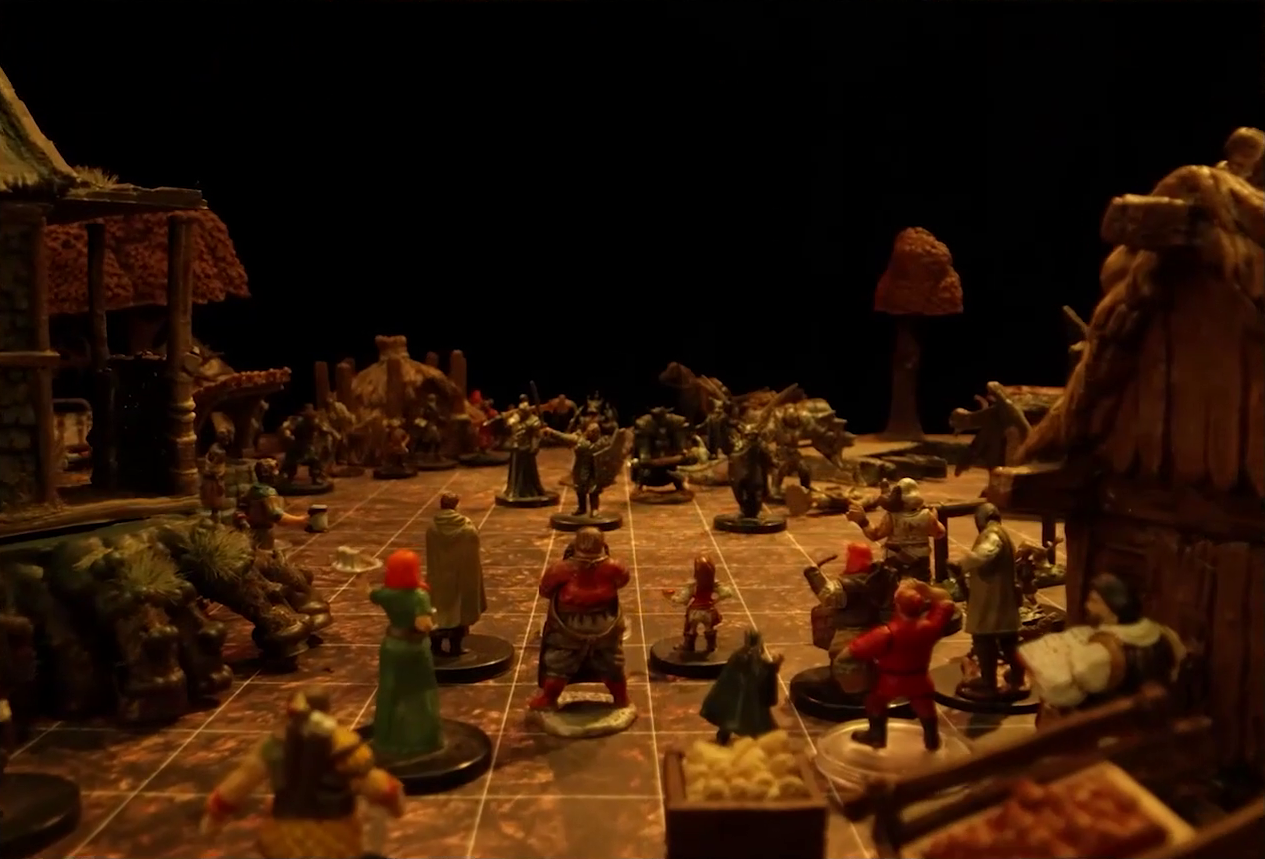 A battlemap focused on a small group of villagers looking towards a group of black-armored soldiers in the center of a small town square. Surrounding the square are small simple buildings made of wood and thatch, a collection of other villagers, and trees in autumn colors.
