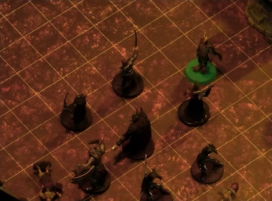 A battlemap focused on a group of six black-armored soldiers surrounding a commander wearing a horned helmet and carrying a large axe. Erro stands near the group. Two villagers lay on the ground next to the soldiers.