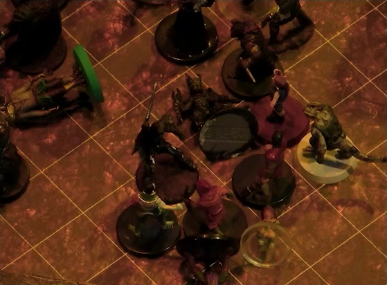 A battlemap focused on a fight between a group of black-armored soldiers and Fiedra, Crokas, and a number of villagers. Erro lays on the ground, with a number of villagers also downed. A soldier lays on the ground in front of Fiedra and Crokas.