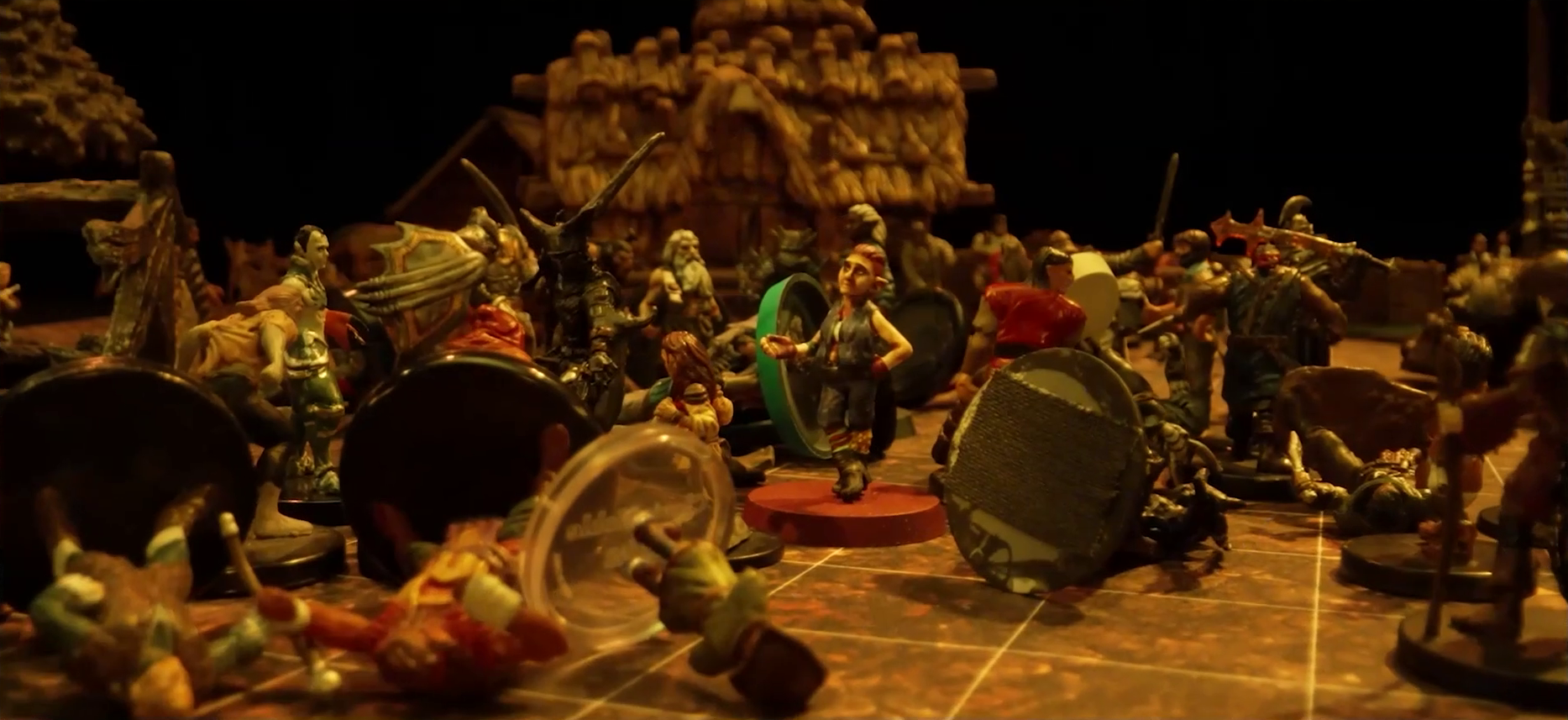 A battlemap focused on Fiedra in the midst of a melee between her, Garen, Rei’nia, and a number of villagers against a group of black-armored soldiers. Erro and Crokas lay on the ground, as do a number of villagers. Visible in the background is a thatch building.