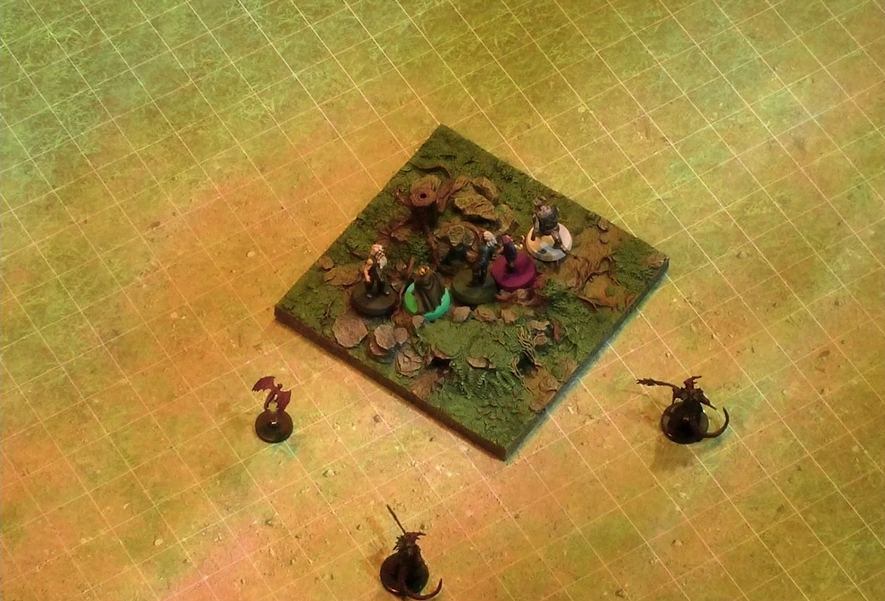 A battlemap of a grassy plain focused on a textured map square, on which are Garen, Erro, Rei’nia, Fiedra, and Crokas. Approaching them are two dragon-like devils armed with barbed pole weapons and a red flying impish creature. The map square is mostly covered in green, with some rocks and a single tree stump.