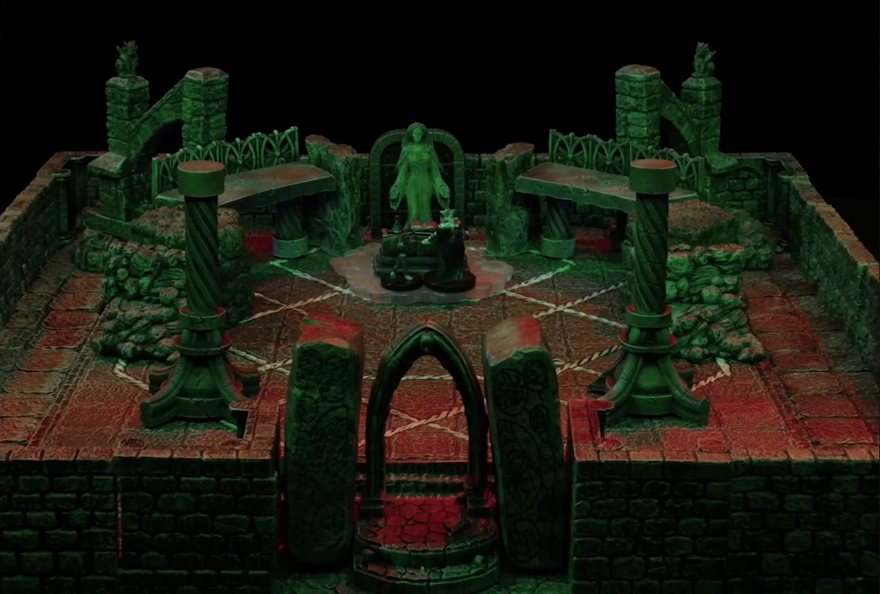 A battlemap of a stone temple interior. Lord Callister and Timothy stand before an altar and statue of the Moonweaver, which sits in front of a dark archway between two stone platforms. The statue stands on a bed of white crystal. The entrance to the room is also an archway, leading to two stone pillars. In the back corners of the room are grotesques placed on buttresses.