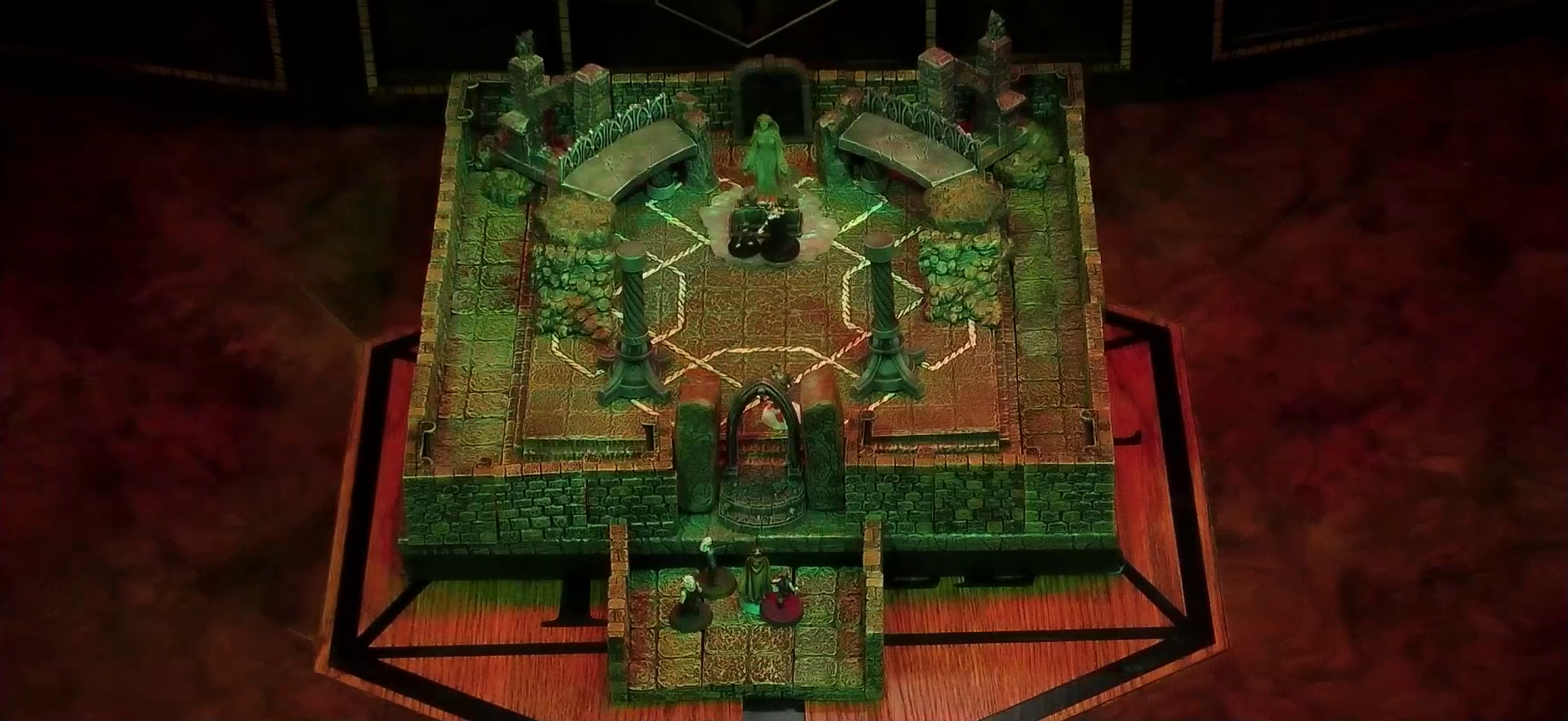 A battlemap of a stone temple interior. Lord Callister and Timothy stand before an altar and statue of the Moonweaver, which sits in front of a dark archway between two stone platforms. The statue stands on a bed of white crystal. Garen, Rei’nia, Erro, and Fiedra stand in the arched entrance to the room while Crokas is a bit beyond within the chamber. Two stone pillars stand near the entrance, and in the back corners of the room are grotesques placed on buttresses.