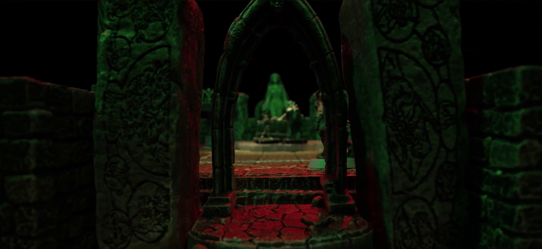 A view of a battlemap through a stone archway decorated with intricate circular carvings. Beyond the archway is a temple chamber with a statue of the Moonweaver at the back. Before the statue stand Lord Callister and Timothy. Just beyond the archway stands Crokas. The floor under the archway is lit in red light.
