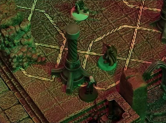 A battlemap of a stone temple interior. Rei’nia and Erro stand next to a stone pillar with a helical pattern of lines running up its length. A red devil stands just behind them. Crokas stands a bit futher into the chamber away from the arched entrance.