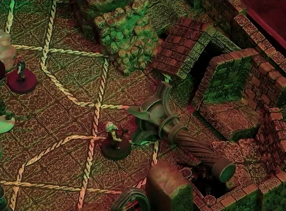 A battlemap of a stone temple interior focused on a toppled stone pillar and rubble, next to which is Garen. The rubble covers where the red tailed devil stood in previous images. Crokas, Fiedra, and Lord Callister are just visible at the left edge of the image. Garen wields a metal hammer in his bare muscular right arm and sports a white beard and hair.
