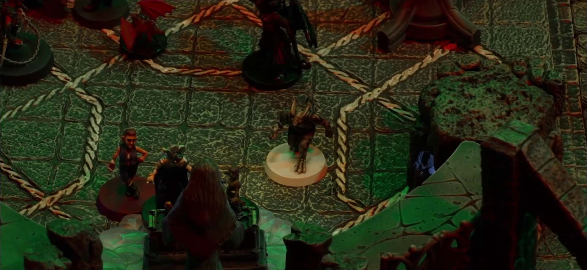 A battlemap of a stone temple interior focused on Crokas, Fiedra, Lord Callister, and Timothy standing before an altar and statue of the Moonweaver. At the top edge of the image are a devil with metallic spikes and pincers, a red winged imp, and a dark devil with wide wings.