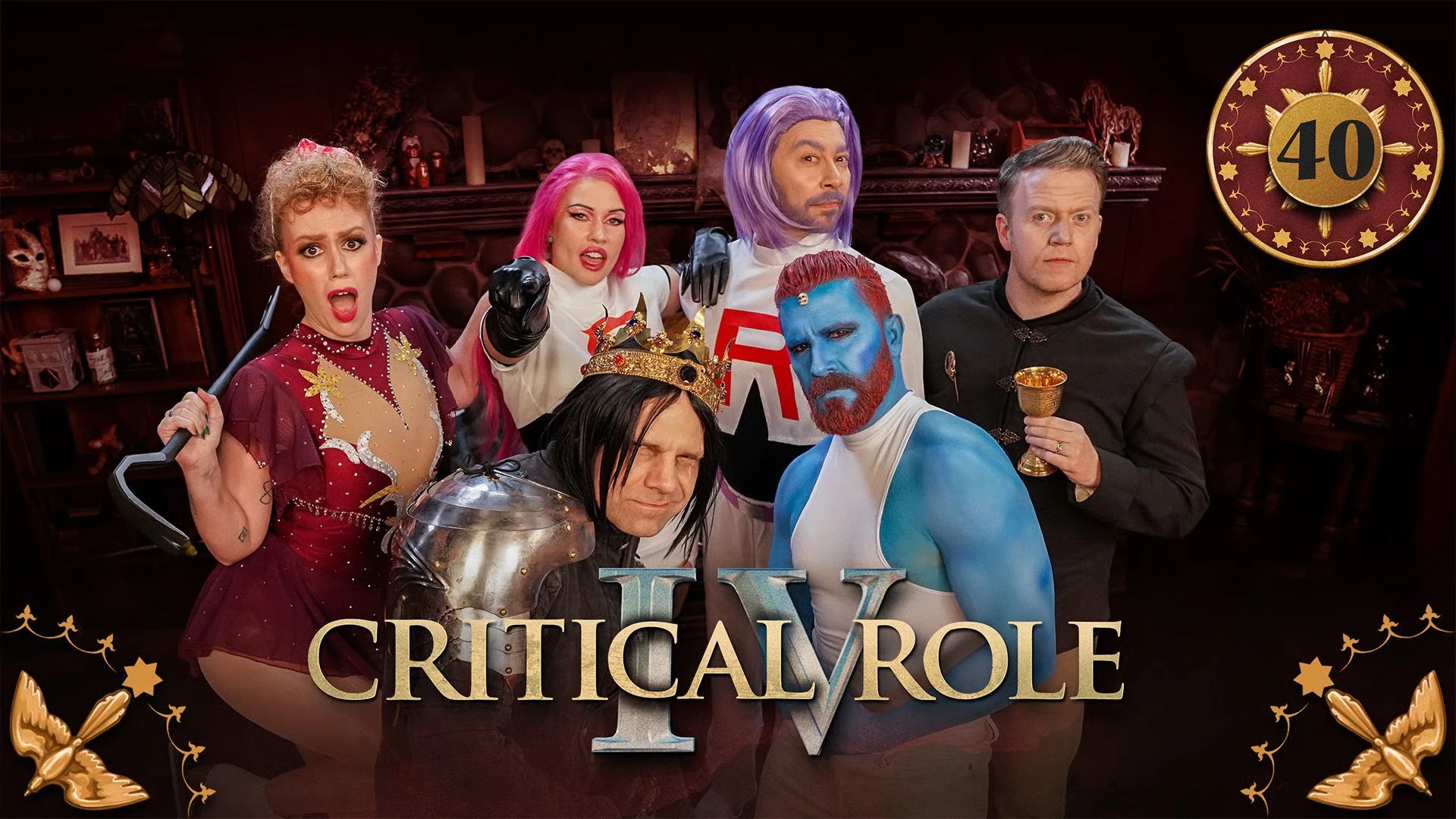 Thumbnail for Critical Role IV episode 40, with a red emblem around the episode number and birds in the bottom corners. The cast of the Schemers table dressed in halloween costumes, posing in a group. Marisha is in a figure skating outfit and holding a crowbar, dressed as Tonya Harding. Whitney and Sam are in pink and blue wigs and white crop tops with red “R”s on them, dressed as Jessie and James from Team Rocket. Liam is in a crown, long black wig, and shoulder plate armor, dressed as Richard III from the play Richard III. Luis is in blue body paint, orange hair dye, white tank top, and a small skull on his forehead, dressed as Mystique from the X-Men. Brennan is in a black formal shirt with a gold pin of a hand with the index finger extended and holds a gold goblet, dressed as Tywin Lannister from Game of Thrones.