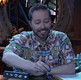 Sam at the table, staring slightly perplexed at a d20 in his hand to determine what he just rolled.