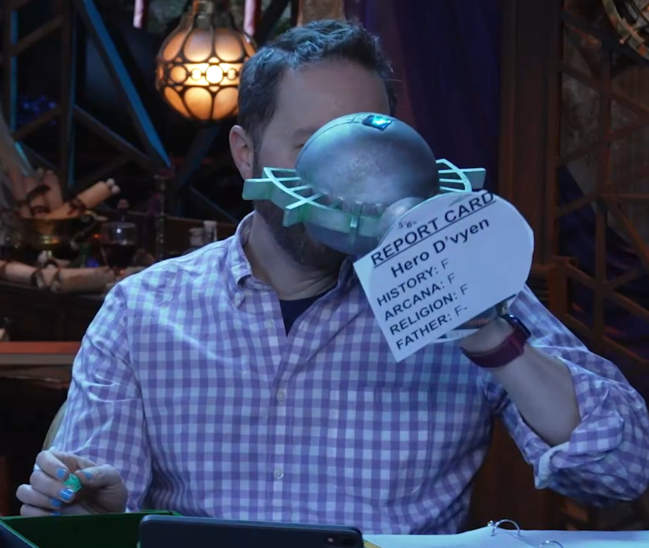 Sam drinking from an ornate silver chalice with the text “REPORT CARD. Hero D’vyen. HISTORY: F. ARCANA: F. RELIGION: F. FATHER: F-” printed on white paper pasted to the bottom. The chalice has spokes emerging from the curve of its cup reminiscent of Candescent Creed sun ray designs. A turquoise gem is set in the side, matching the gem in Wicander’s circlet. Sam tips the chalice horizontally into his mouth.